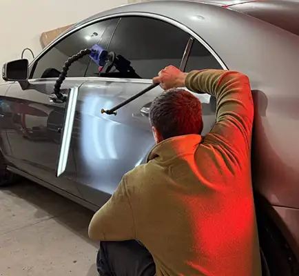 Paintless dent repair technician removing door ding in Spokane Valley